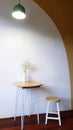 White Flower In Vase On Table, Wooden Stool Chair With Vintage Light On Top With Concrete Wall And Orange Or Brown Pastel Painted.