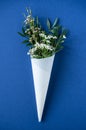 White flowers in paus tracing paper cone on blue background