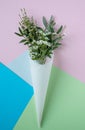 White flowers in paus tracing paper cone on colored paper background