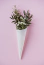 White flowers in paus tracing paper cone on pink background