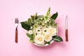 White flowers on plate, fork, knife over pastel pink background. Healthy eating, vegan diet concept. Creative layout. Top view, Royalty Free Stock Photo