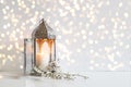 White flowers, prunus tree blossoms and glowing silver decorative Moroccan lantern on table background with golden bokeh