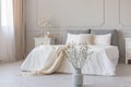 White flowers in vase in elegant grey bedroom interior with simple bedding Royalty Free Stock Photo