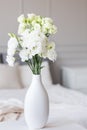 White flowers in vase in elegant grey bedroom interior with simple bedding Royalty Free Stock Photo