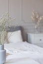 White flowers in vase in elegant grey bedroom interior with simple bedding Royalty Free Stock Photo