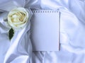 White flowers on a white background and a notepad for notes. Flower arrangement with white roses is a wedding bouquet. Royalty Free Stock Photo