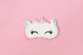 White fluffy fur sleep mask unicorn with closed eyes and small ears on pastel pink paper background, copy space. Top view, flat