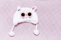 White fluffy hat in the shape of a cat`s face - accessories for little girls in winter on a pink knitted wool blanket Royalty Free Stock Photo