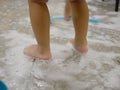 White foam and air bubbles at baby`s feet on the bathroom floor, as she is haveing fun learning to clean a restroom Royalty Free Stock Photo