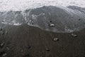 White foam waves wash over the dark lumpy beach