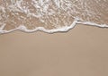 White foamy wave on the beach sand. Top view. Marine texture background