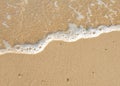 White foamy wave on the beach sand. Top view. Marine texture background