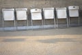 White folded chairs in the row on concrete background. Stacking chairs in Public space.