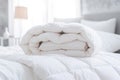 White folded duvet lying on white bed background. Preparing for winter season, household, domestic activities, hotel or Royalty Free Stock Photo