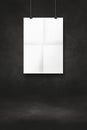 White folded poster hanging on a black wall with clips Royalty Free Stock Photo