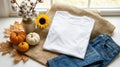 White folded t shirt displayed on burlap with autumn decor Royalty Free Stock Photo