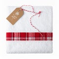 White Folded Towel with Red Plaid Band and Gift Tag on White Surface Royalty Free Stock Photo