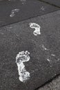 Footprints on asphalt road. Caution, freshly painted!