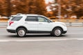White Ford Explorer is driving on the highway road with an autumn urban background