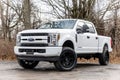 White 2020 Ford F-250 pickup truck with lifted wheels on a dirt road