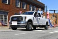 A white ford truck driving through the fourth of July Parade
