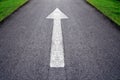 White forward arrow sign on grey asphalt road .