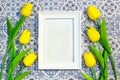 White frame on a blue and white tile background surrounded by yellow tulips Royalty Free Stock Photo