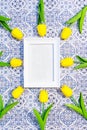 White frame with with free space on a blue and white tile background surrounded by yellow tulips Royalty Free Stock Photo