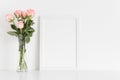 White frame mockup with a bouquet of pink roses in a glass vase on a white table. Portrait orientation Royalty Free Stock Photo