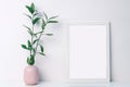 White frame mockup with a pink notched vase with twigs with green leaves