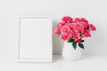 White frame mockup and pink roses bouquet in a white vase. Copy space for text Royalty Free Stock Photo