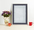 White frame mockup with plant pot, mug and apple on wooden shelf Royalty Free Stock Photo