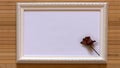 White frame with one dried red rose and empty white canvas on natural bamboo wall. Royalty Free Stock Photo