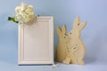 White frame for a photo with white flowers on a blue background and a wooden figurine of a family of bunnies Royalty Free Stock Photo