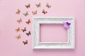 White frame on pink background with multicolored wooden butterflies summer composition