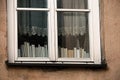 White frame window in old town building with curtains and books standing on a sill indoors Royalty Free Stock Photo