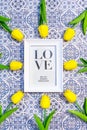 White frame with the word blue on a blue and white tile background surrounded by yellow tulips Royalty Free Stock Photo