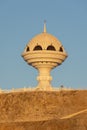 White Frankincense Burner Monument in Riyam Park in Old Town, Muscat, Oman as the glowing sun sets over the mountain