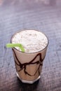 White Frappe Coffee Glass with iced drink with chocolate syrup on a dark wooden table in a cafe.