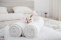 White and fresh laundered fluffy towels with flower on bed in ho