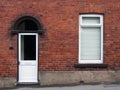 White front door and window of a typical old brick british terraced house with white windows and blinds