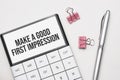 White future calculator, paper sheet, pink paper clips and silver colored pen. Text Make a good first impression Royalty Free Stock Photo