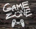 White gamepad on a dark wooden background. phrase game zone written in white Royalty Free Stock Photo