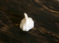 White garlic head on a dark brown wooden background.