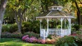 White Gazebo Surrounded by Flowers and Trees Royalty Free Stock Photo