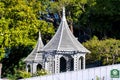 White gazebos two in park or outdoor schoolyard with pointy spires with white fence and background green trees Royalty Free Stock Photo