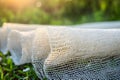 White geotextile mesh roll on grass in warm evening light showing texture and porous structure Royalty Free Stock Photo