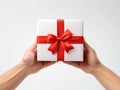 White gift box in hand, tied with red ribbon on a white background. AI-Generated
