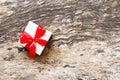 White gift box with perfect red ribbon bow on wooden table background in top view with copy space. Royalty Free Stock Photo