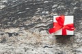 White gift box with perfect red ribbon bow on wooden table background in top view with copy space. Royalty Free Stock Photo